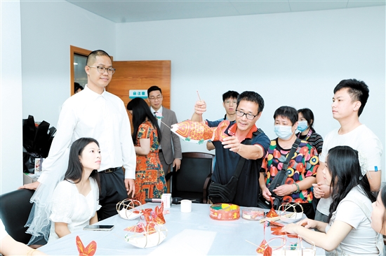 昨日，在新會(huì)區(qū)民政局婚姻登記處，工作人員向剛領(lǐng)證的新人們展示新會(huì)魚(yú)燈制作技巧。