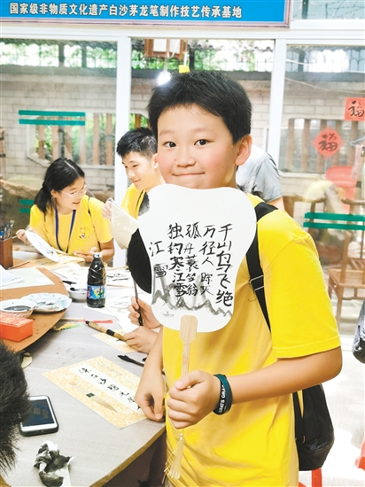 美國華裔青少年李恩誠用茅龍筆在扇面上寫下唐詩。