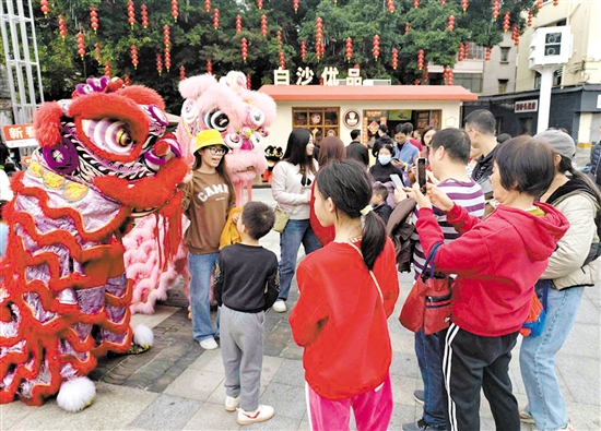 游客在長堤歷史文化街區(qū)與醒獅合影。何雯意