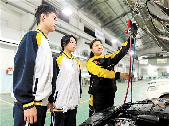 黃錚（右一）在汽修實(shí)訓(xùn)車間指導(dǎo)學(xué)生。