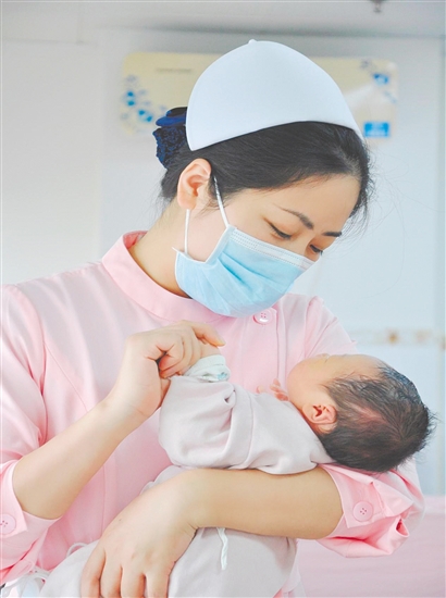 這是一雙托起生命的手。江門市中心醫(yī)院愛嬰?yún)^(qū)主管護師湯玲玲正在安撫哭鬧的寶寶。她一手環(huán)住襁褓，一手牽起寶寶的小手，動作舒緩而溫柔。在這里，生命的啼哭與溫柔的守護相遇，匯聚成世間至暖的力量。（林錦棠