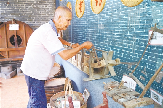 新華村打造農(nóng)耕文化展館，留住鄉(xiāng)村記憶。圖為村中老人向記者介紹農(nóng)具。