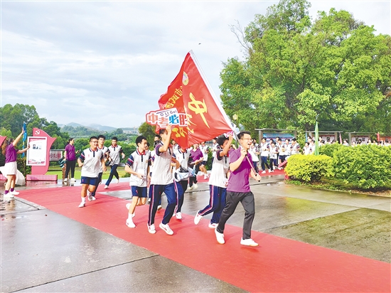 在臺(tái)山市武溪中學(xué)，老師揮舞著“中考加油”的紅旗為考生加油助威。