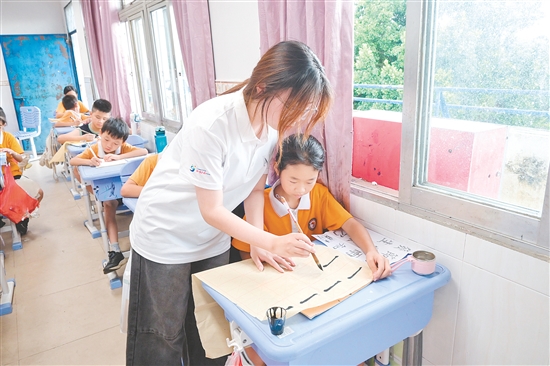 社會實踐隊隊員指導(dǎo)學(xué)生練習(xí)硬筆、軟筆書法。