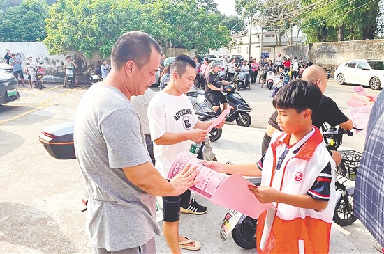 學(xué)生志愿者向等候接孩子的家長發(fā)放基孔肯雅熱防控宣傳單。
