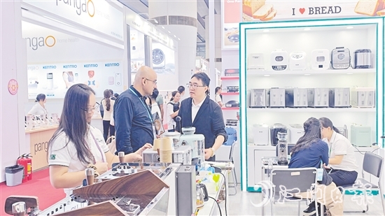 外國客商在一家蓬江區(qū)家電企業(yè)的展區(qū)前洽談合作。任佳燕